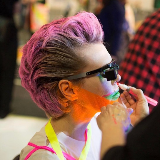 A person having colorful makeup applied while wearing eyetap